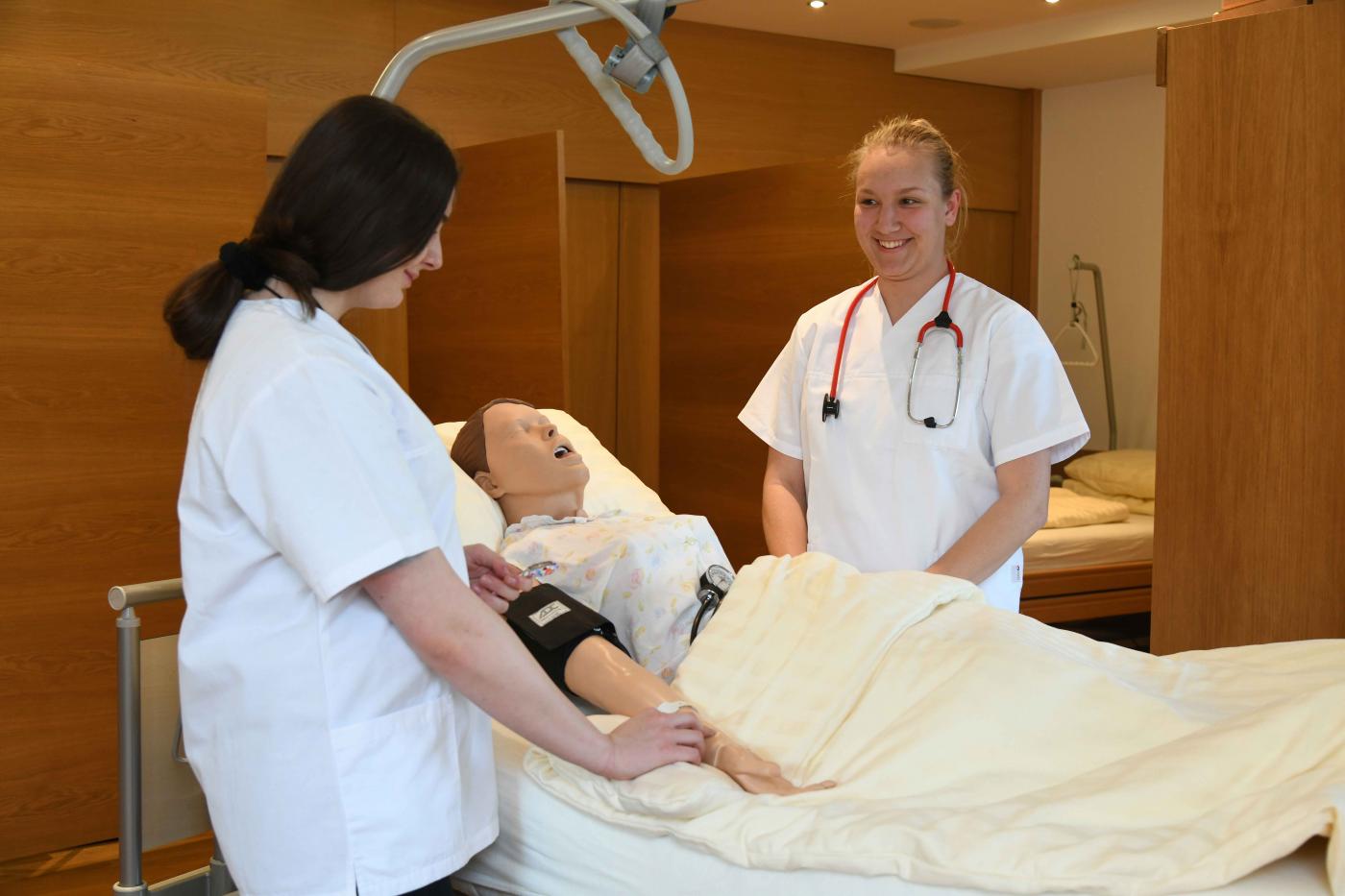 Schülerinnen bei der Pflegeausbildung - Patientenpuppe liegt im Bett