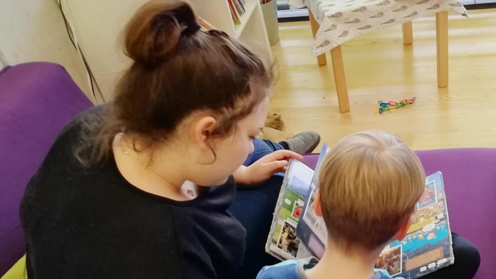 Assistenzkraft liest Kind ein Buch vor