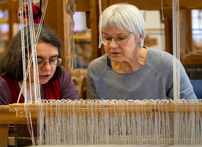 Dame beim Weben am Webstuhl